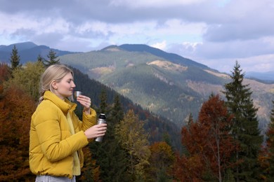 Photo of Young woman with drinking hot beverage in mountains