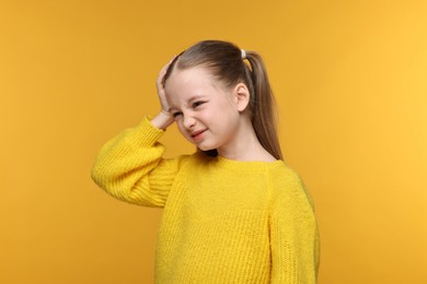 Photo of Little girl suffering from headache on yellow background