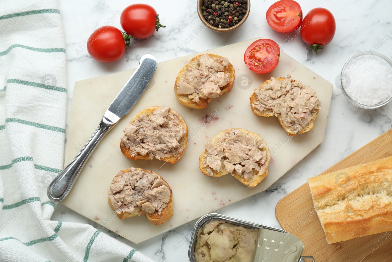 Photo of Tasty sandwiches with cod liver on white marble table, flat lay