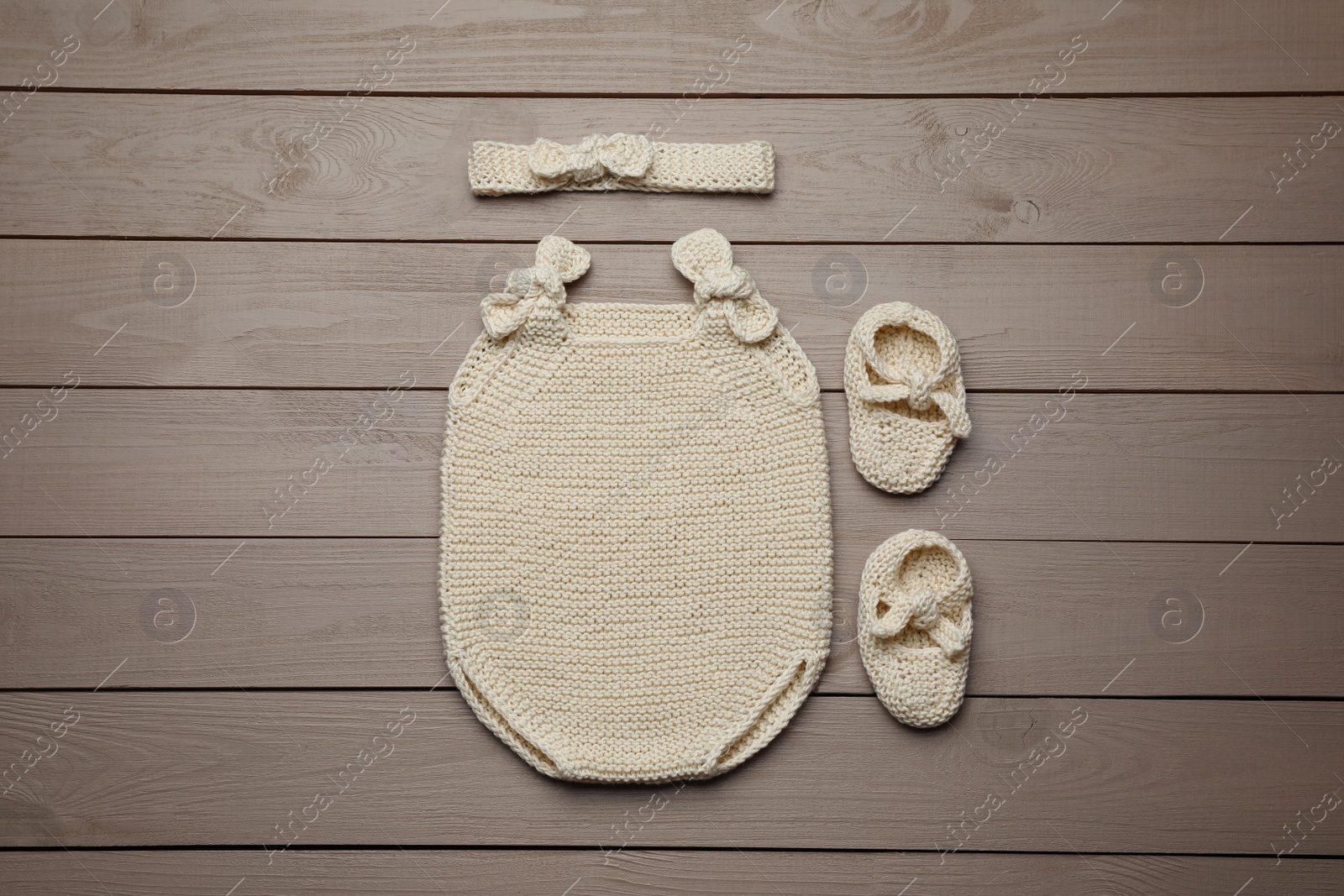 Photo of Set of cute baby knitwear for photoshoot on wooden background, flat lay