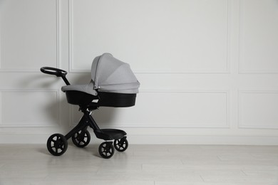 Photo of Baby carriage. Modern pram near white wall, space for text