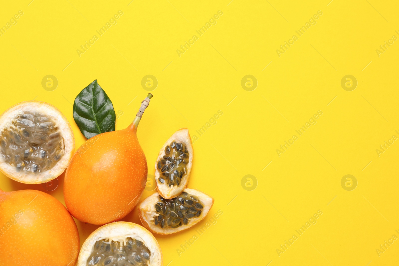 Photo of Delicious ripe granadillas with leaf on yellow background, flat lay. Space for text