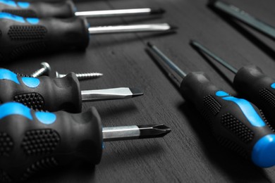 Photo of Set of screwdrivers on black wooden table, closeup