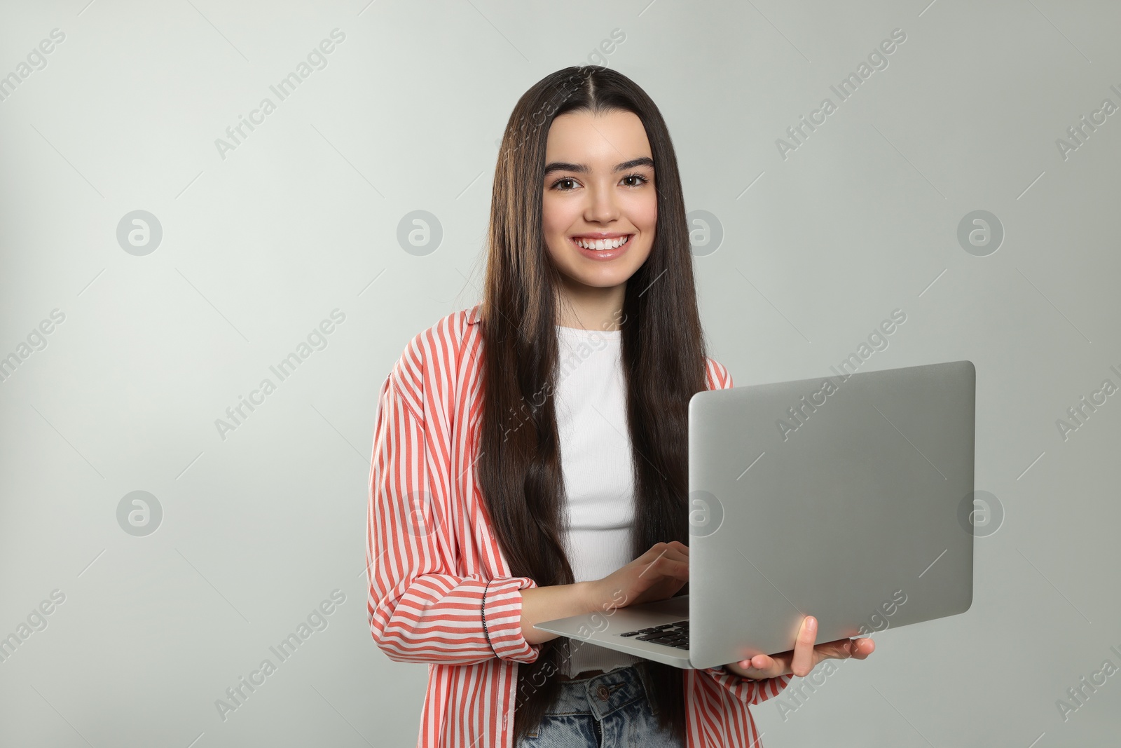 Photo of Teenage girl with laptop on light grey background