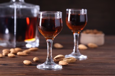 Liqueur glasses with tasty amaretto and almonds on wooden table, closeup