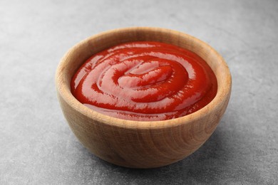 Bowl of tasty ketchup on light grey table, closeup