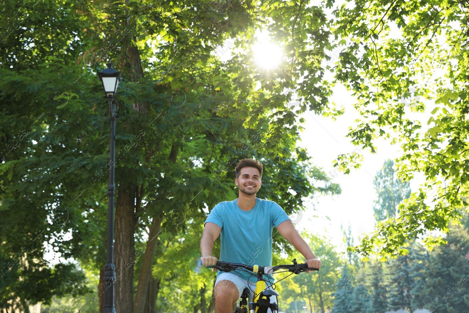 Photo of Handsome young man riding bicycle on city street, low angle view