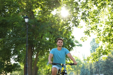 Photo of Handsome young man riding bicycle on city street, low angle view