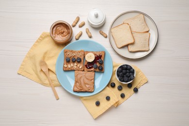 Different tasty toasts with nut butter and products on white wooden table, flat lay