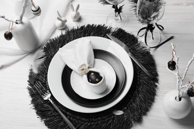 Photo of Festive table setting with bunny ears made of black egg and napkin. Easter celebration