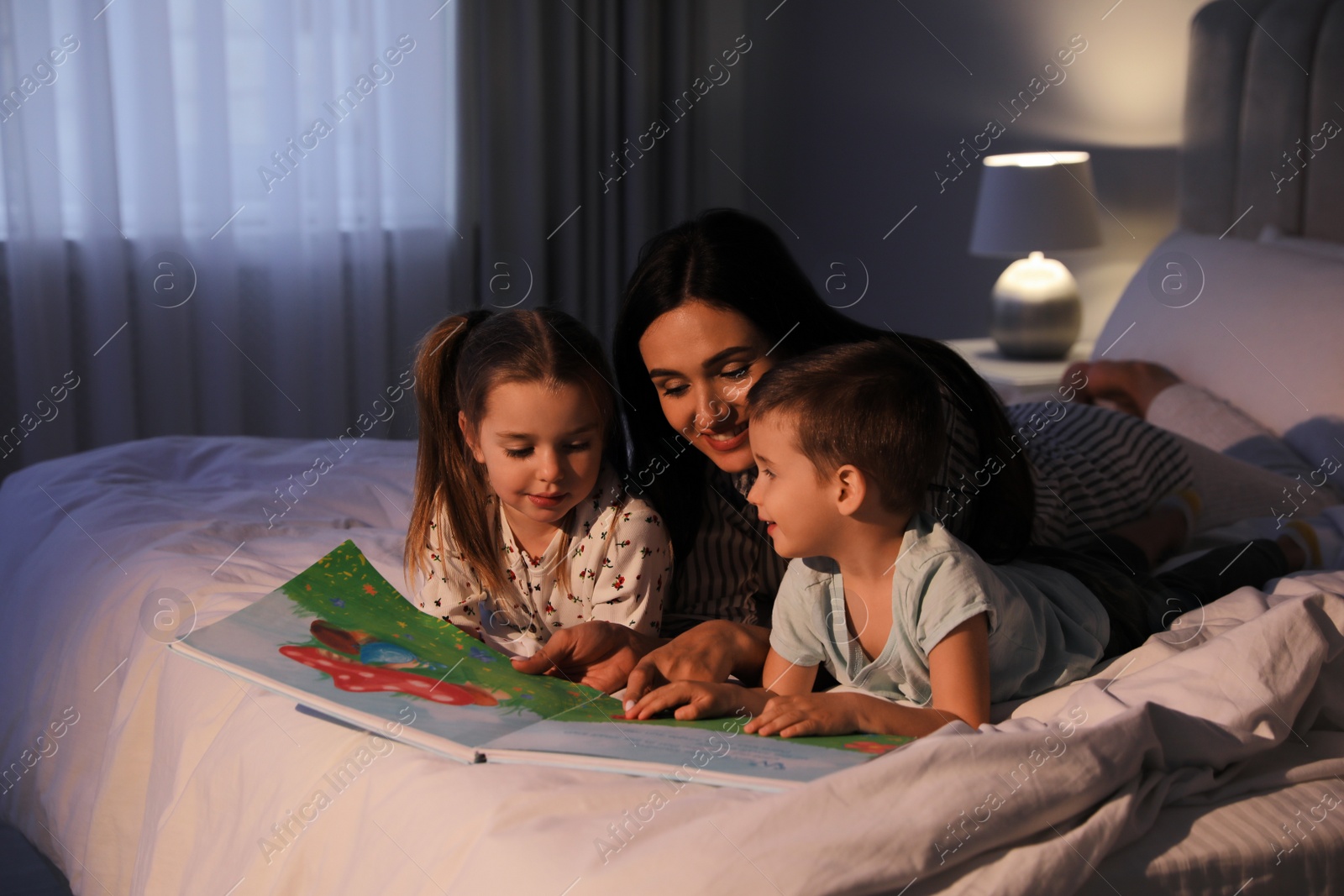 Photo of Mother reading bedtime story to her children at home