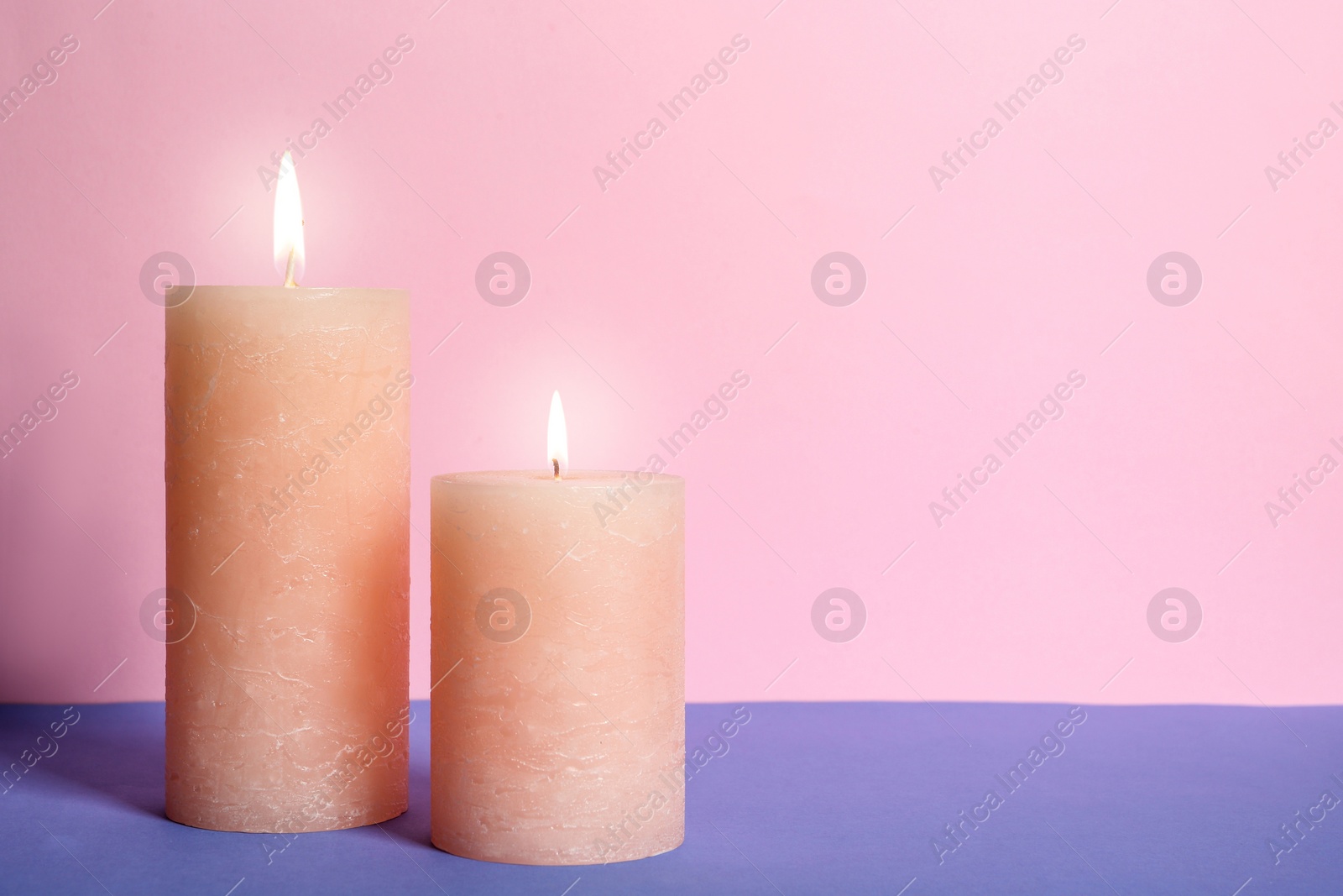 Photo of Decorative wax candles on table against color background