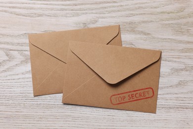 Image of Top Secret stamp. Paper envelopes on wooden table, top view
