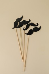 Fake paper mustaches party props on beige background, flat lay