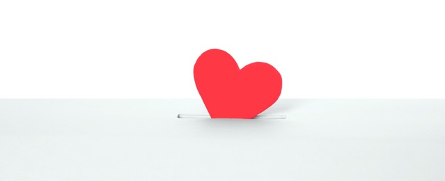 Photo of Red heart into slot of donation box against white background