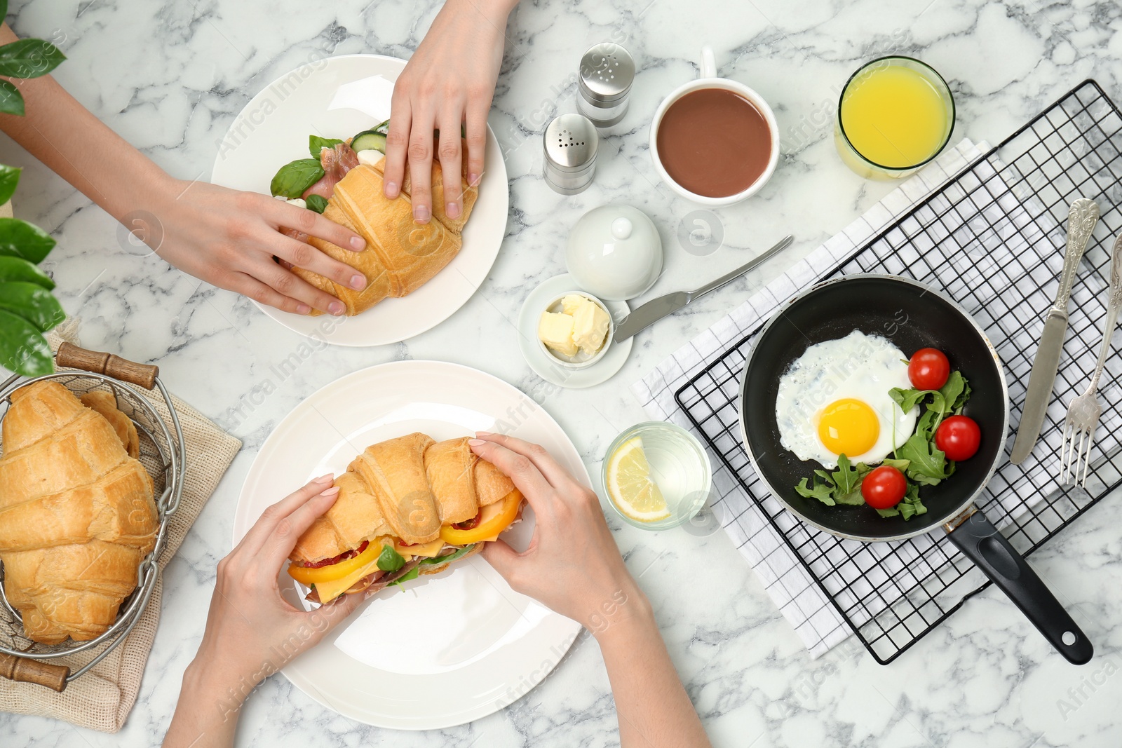 Photo of People eating tasty croissant sandwiches at table