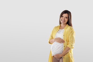 Happy young pregnant woman on white background, space for text
