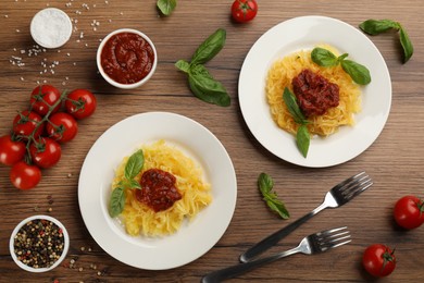 Photo of Tasty spaghetti squash with basil and tomato sauce served on wooden table, flat lay