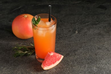 Photo of Tasty grapefruit drink with ice and mint in glass on dark textured table. Space for text