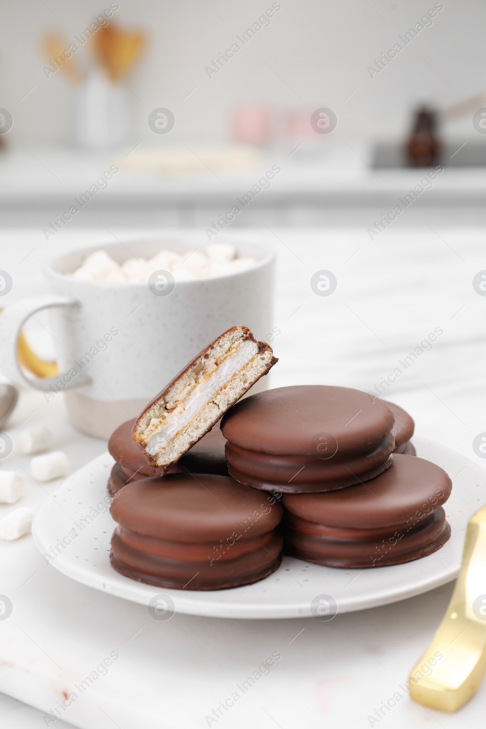 Photo of Saucer with delicious choco pies and cup of drink on white table in kitchen