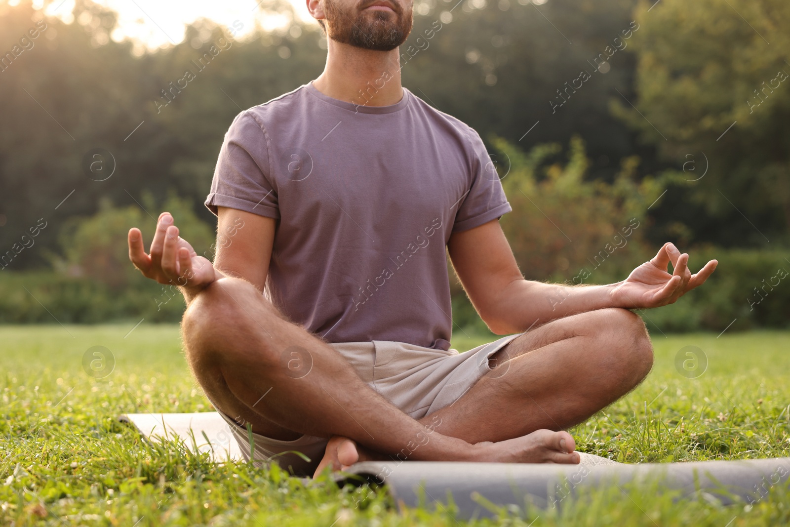 Photo of Man practicing yoga on mat outdoors, closeup. Lotus pose