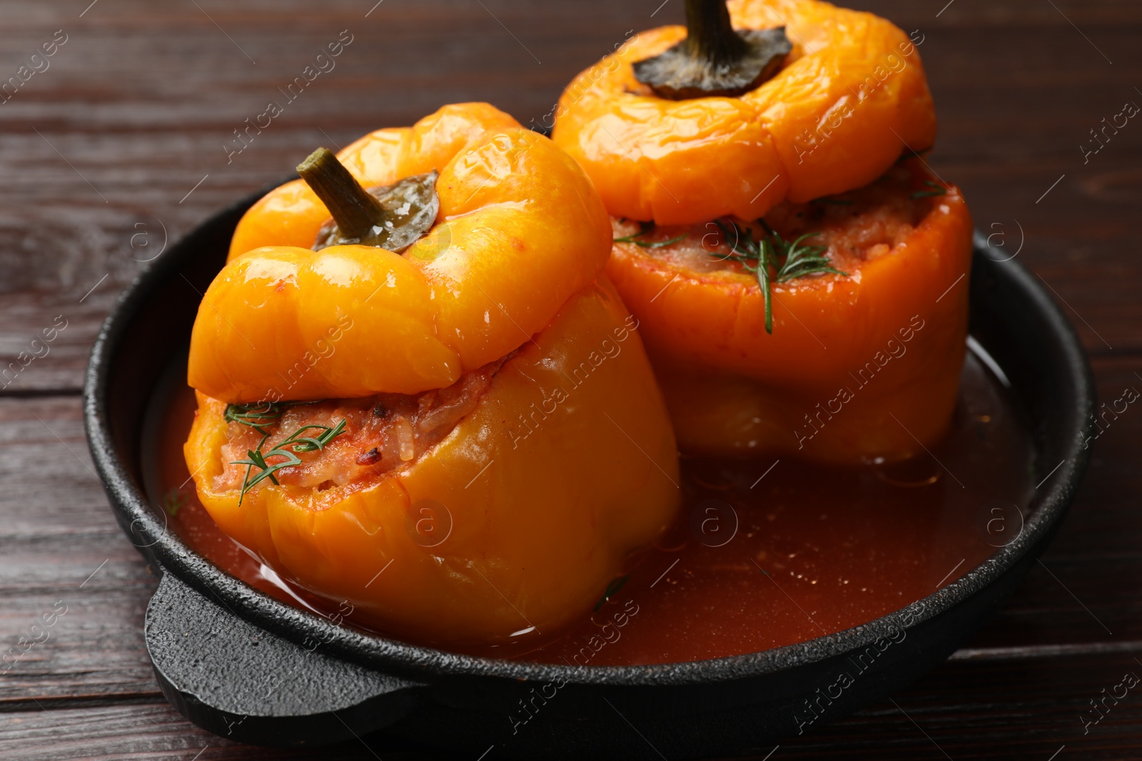 Photo of Tasty stuffed peppers in pan on wooden table, closeup