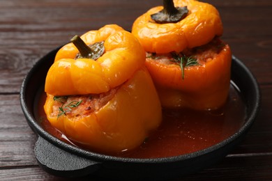 Photo of Tasty stuffed peppers in pan on wooden table, closeup