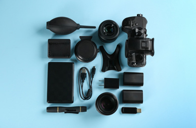 Photo of Flat lay composition with camera and video production equipment on light blue background