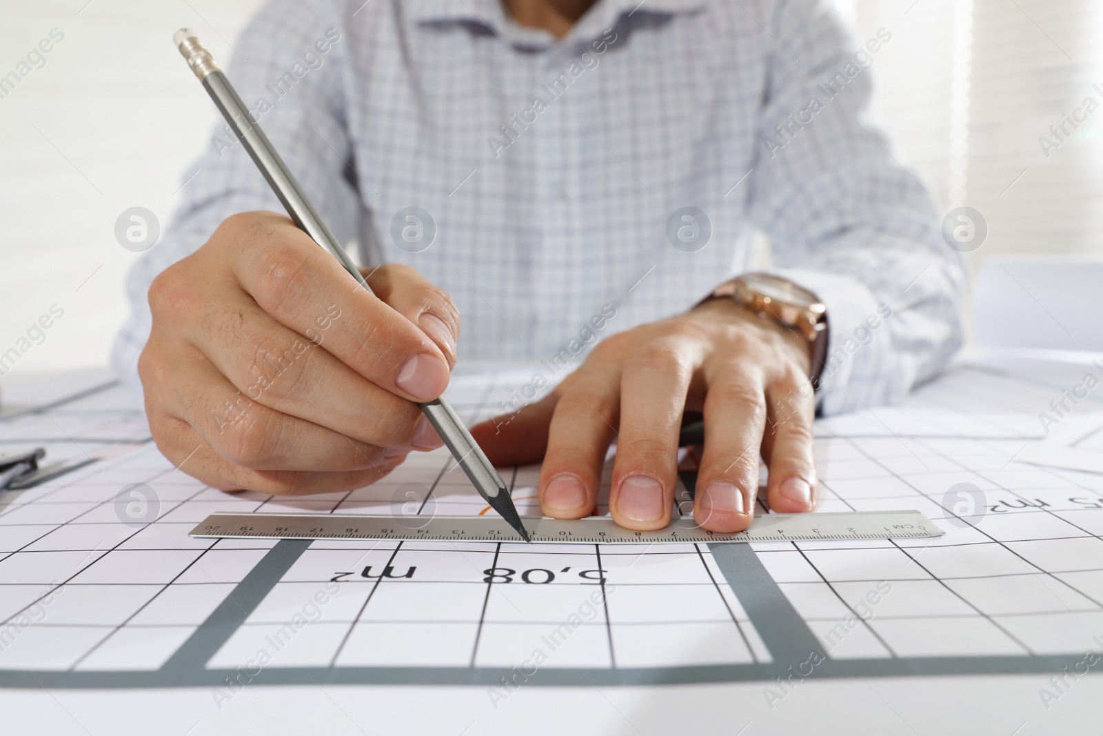 Photo of Architect working with construction drawings indoors, closeup