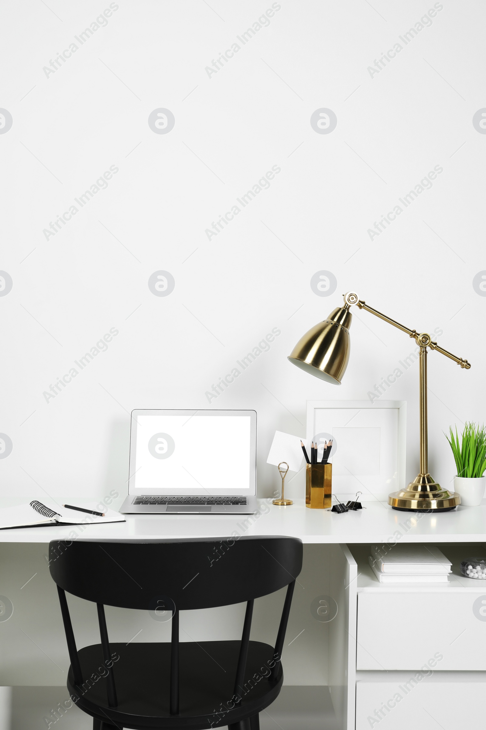 Photo of Cozy workspace with laptop, lamp and stationery on wooden desk at home