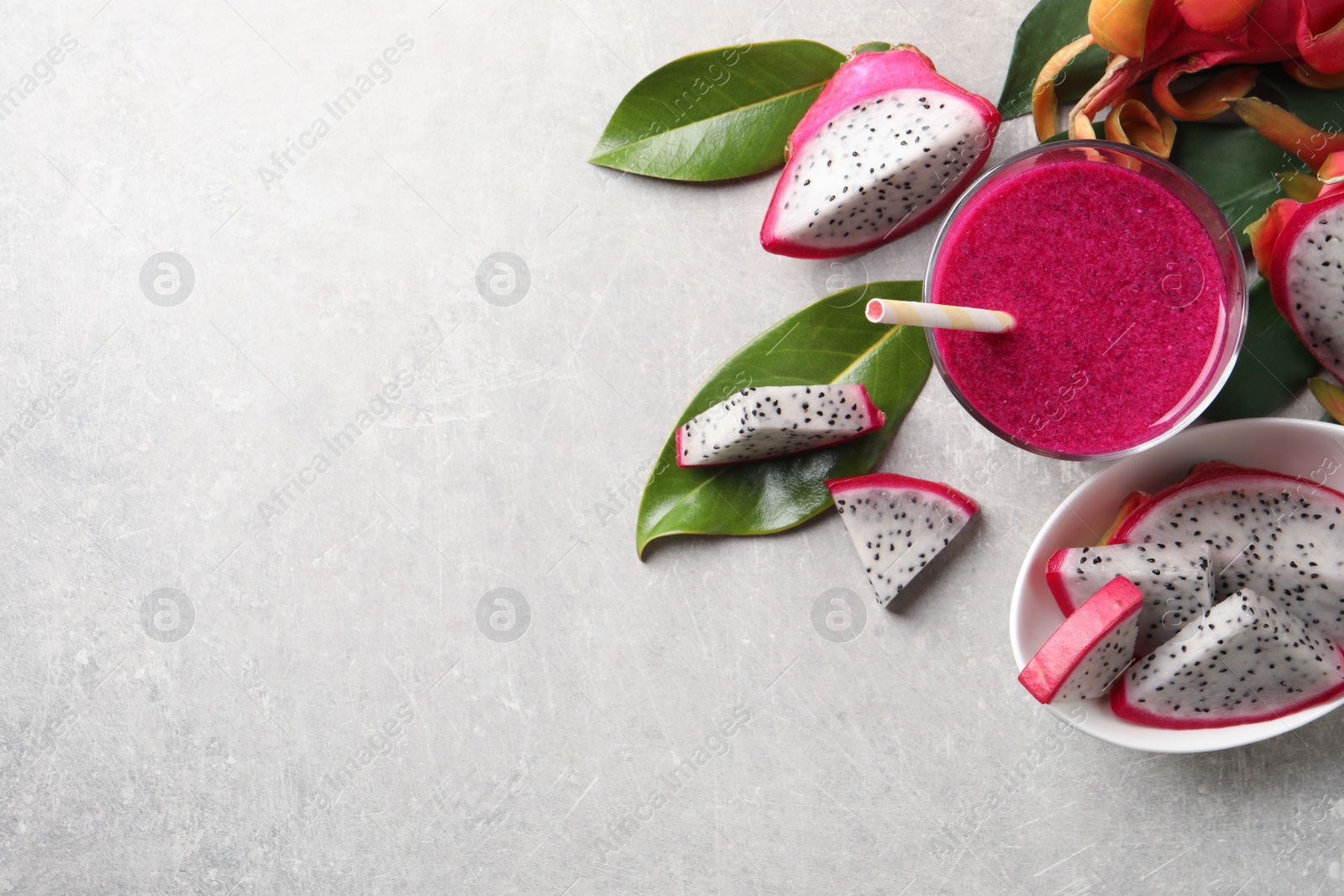 Photo of Delicious pitahaya smoothie and fresh fruits on light grey table, flat lay. Space for text