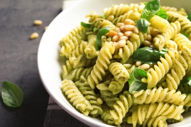 Plate with delicious basil pesto pasta on gray table