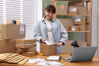 Parcel packing. Post office worker sticking barcode on box at wooden table indoors