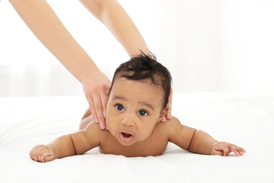 Photo of Mother and her cute child on bed indoors. Baby massage and exercises