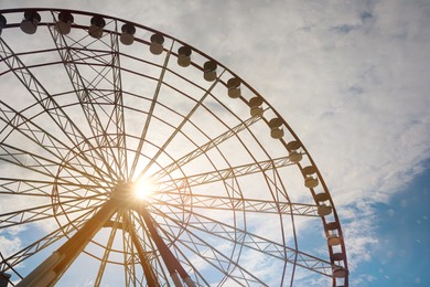 Photo of Beautiful large Ferris wheel against blue cloudy sky on sunny day, low angle view