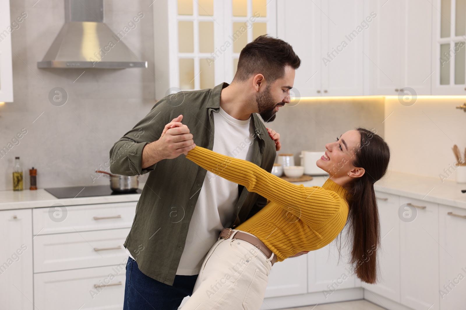 Photo of Happy lovely couple dancing together in kitchen