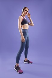 Photo of Woman in sportswear and headphones on violet background