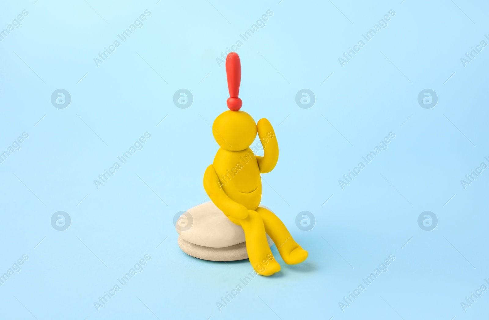 Photo of Human figure made of yellow plasticine with exclamation mark as solution idea on light blue background
