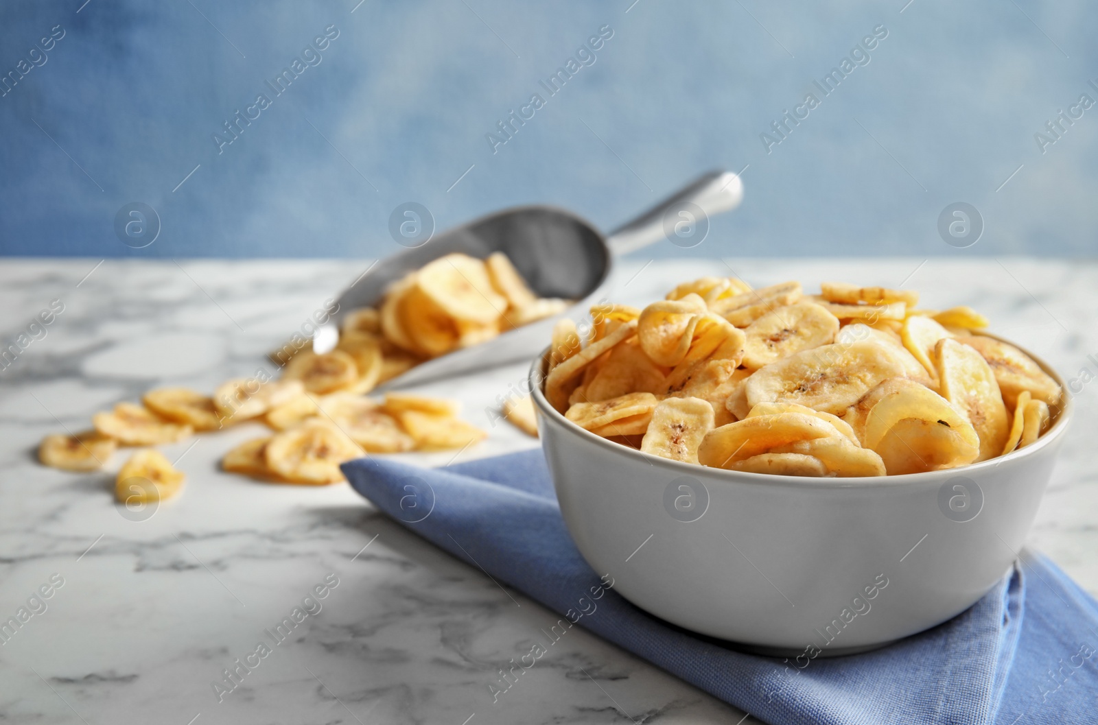 Photo of Bowl with sweet banana slices on marble table, space for text. Dried fruit as healthy snack