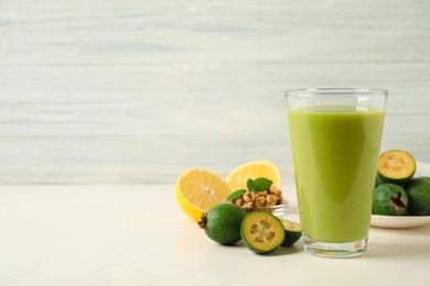 Fresh feijoa smoothie in glass on white table, space for text