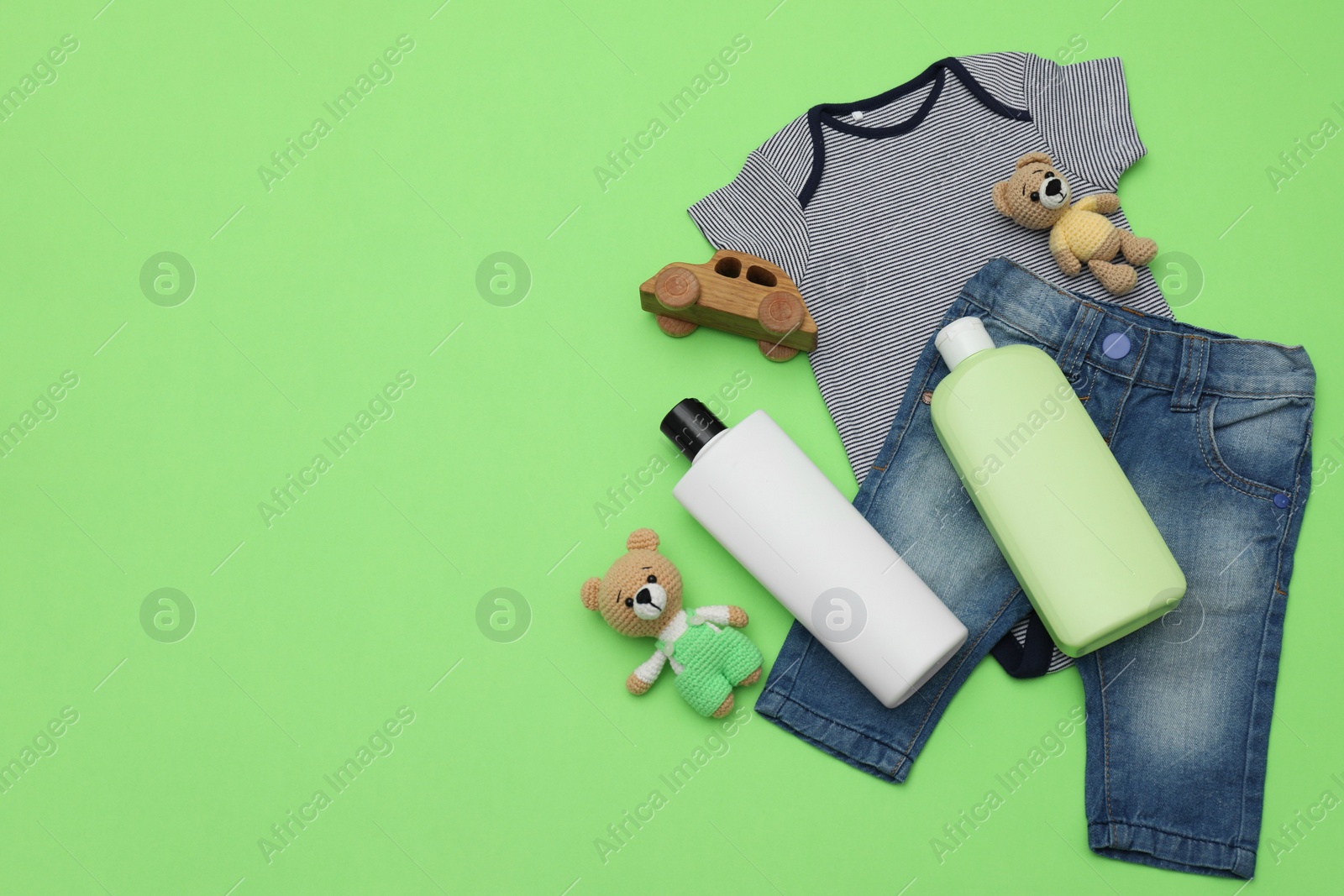 Photo of Bottles of laundry detergents, baby clothes and toys on light green background, flat lay. Space for text