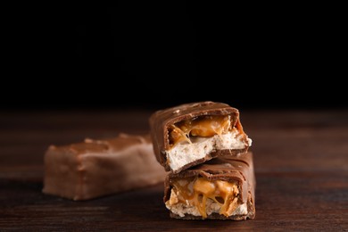 Photo of Chocolate bars with caramel, nuts and nougat on wooden table, closeup