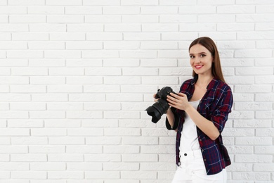 Photo of Professional photographer with modern camera near white brick wall. Space for text