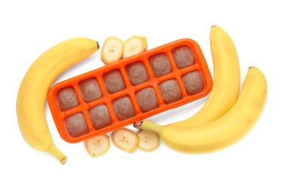 Photo of Banana puree in ice cube tray and ingredients on white background, top view. Ready for freezing