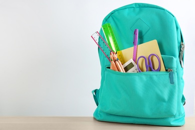 Photo of Different school stationery in backpack on table against white background, space for text. Back to school