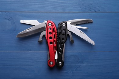 Photo of Modern compact portable multitool on blue wooden table, top view