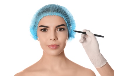Doctor holding marker near young woman's face isolated on white. Plastic surgery concept