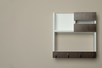 Photo of Wooden key holder on beige wall. Space for text