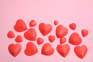 Small paper hearts on color background, top view