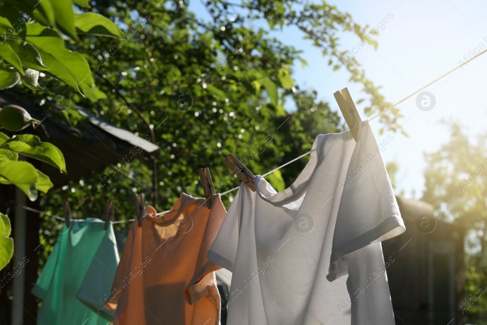 Photo of Washing line with clean laundry and clothespins outdoors, closeup